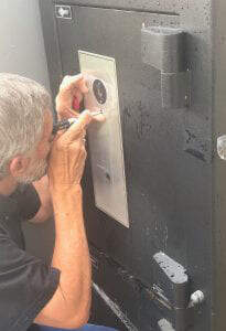 Man using tool to look into panel on front of a black safe