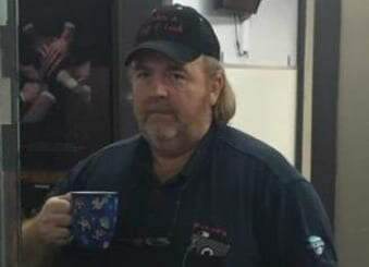Man standing with a blue mug with a black cap on his head